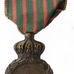 Round medal with raised text. Red and green striped ribbon.