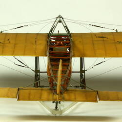 Model aeroplane with exposed wooden frame and off white panelling. Back view.