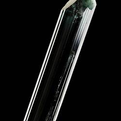 Dark green prsimatic crystal on black background.