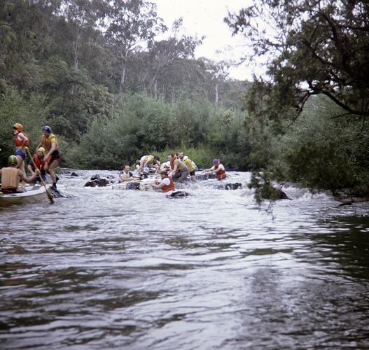 People on rafts in river rapids.