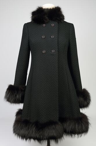 Black woollen double-breasted coat with fur collar, cuffs and hem. Six plastic buttons.