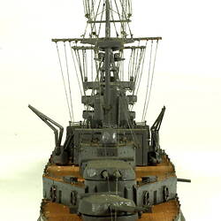 Naval ship with mast, front view.