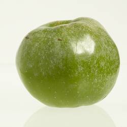 Wax model of an apple painted green.