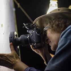 Researcher taking photograph of moth on white sheet at night.