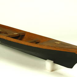 Wooden boat with black hull, three quarter view.