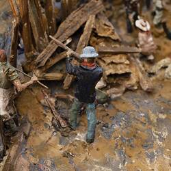 Detail of man firing a gun in a larger model of figurines representing soldiers and miners engaged in fighting