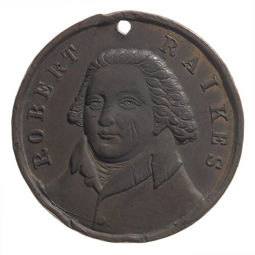 Round copper medal with three-quarter bust of male facing left. Text above.