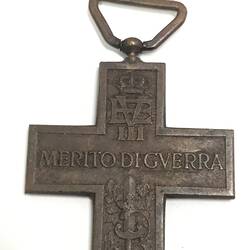 Dark metal cross medal with raised text and decorations. Loop at top.