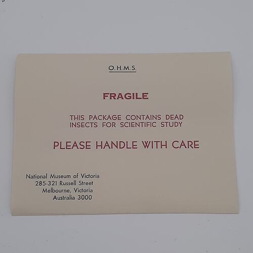 Rectangular paper label with black and red text.