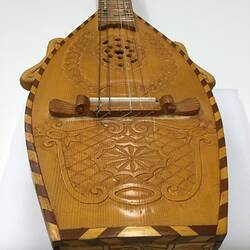 Detail of brown wooden mandolin body. Carved patterns.