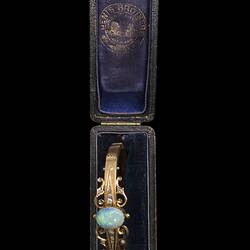 Gold bracelet with central oval white opal, supported by rose cut diamonds and delicate gold filigree-style detail. In navy case.