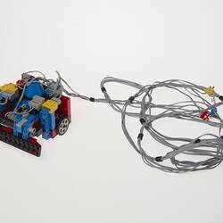 Grey cables attached to black, blue, red, yellow and grey plastic component.