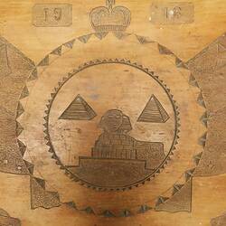 Wooden tray carved with sphinx, pyramids, flags and cannon. Detail.