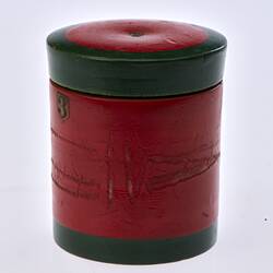 Red painted, cylindrical wooden box. Dark green trim around lid and base.