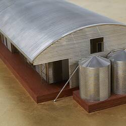 Model of a house with an arched roof, corrugated iron and wide expanses of glass.