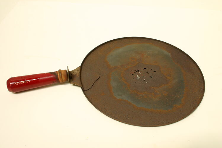 Circular plate with shallow lip and red painted, wooden handle.