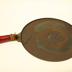 Circular plate with shallow lip and red painted, wooden handle.