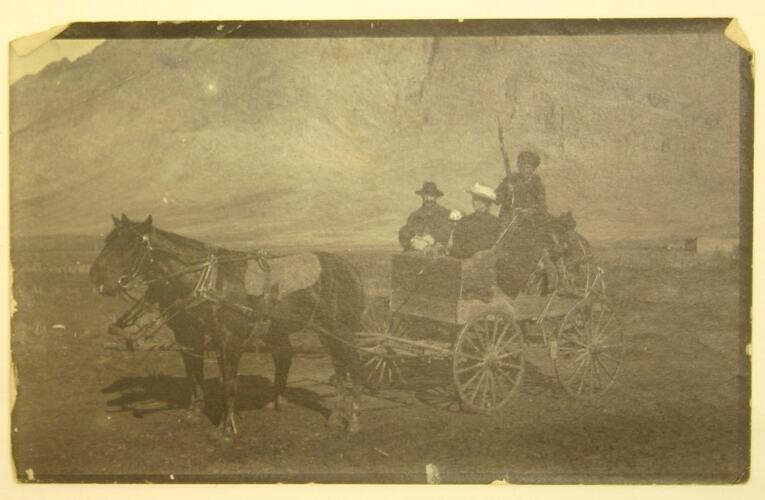 Group of people in cart being pulled by two horses.