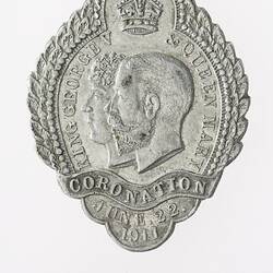 Silver medal with crown in top-centre and profile of two men in centre, banner with text below.