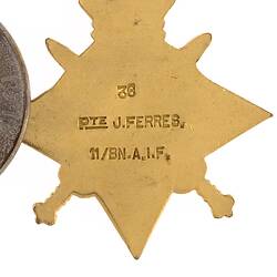 Four pointed star shaped medal with red, white and blue ribbon, back view.