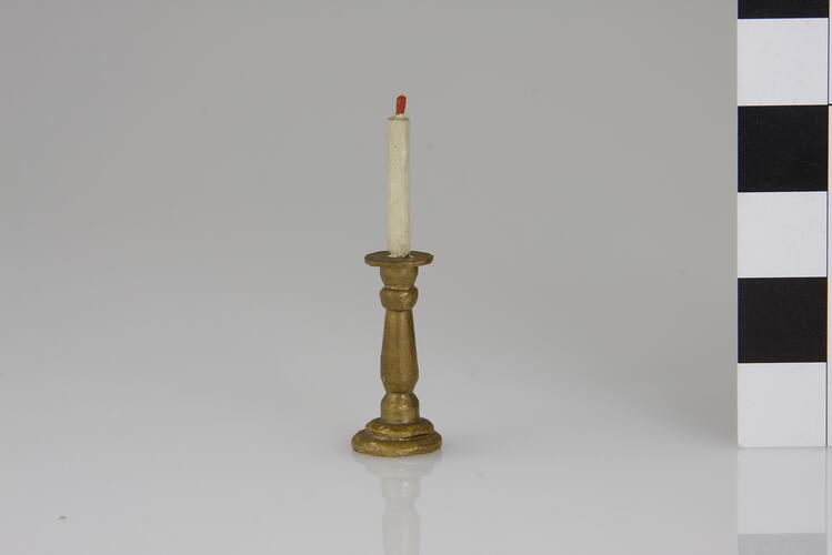 Gold coloured candle stick and white candle.