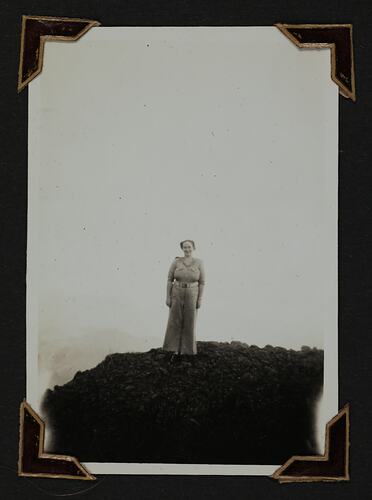 Woman in uniform standing on a cliff.