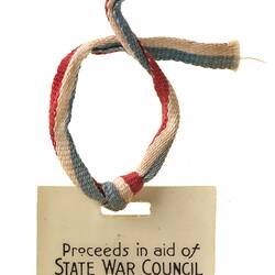 Plastic badge with printed text and red, white and blue textile ribbon.