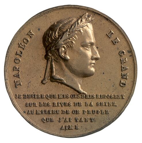 Round medal with male profile facing right. Text below and around.