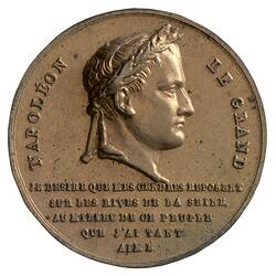 Round medal with male profile facing right. Text below and around.