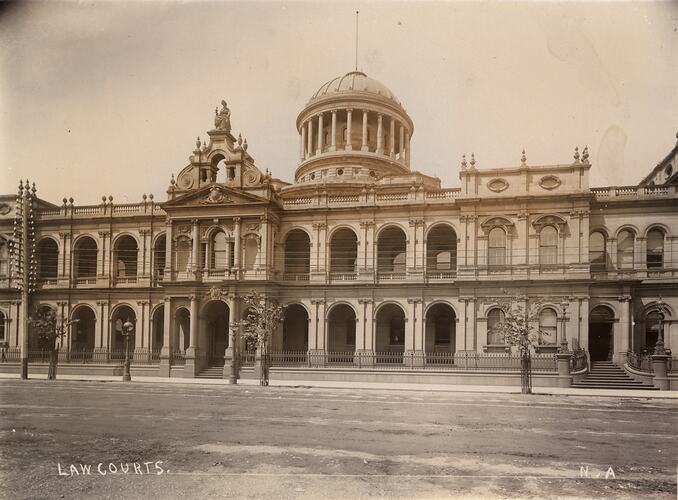 Ornate building front entrance with dome. Above entrance is a classical stone sculpture of female figure representing 'Justice'.