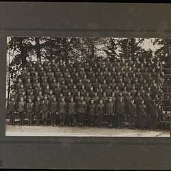 Group portrait of men in military uniform arranged in rows on tiered benches.