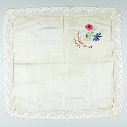 Square white cloth with embroidered flowers at top left, back