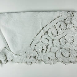 Folded detail of white cutwork embroidery.