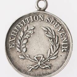 Silver medal with wreath, text surrounding. Loop at top.