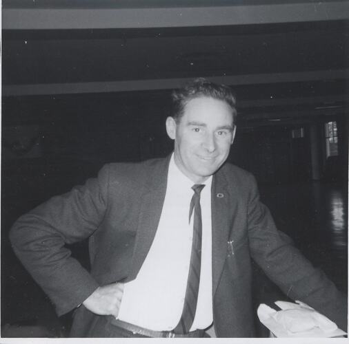Man in suit smiles and leans on counter.