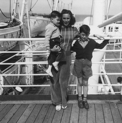 Woman and two children standing on ship deck.