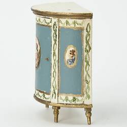 Semi-circular bedside table painted blue and cream with gold edging. Central oval portrait on front and left.