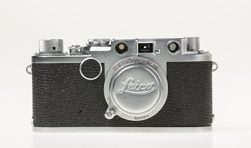 Black camera with metal trim, cap, lens, dials at top corners.