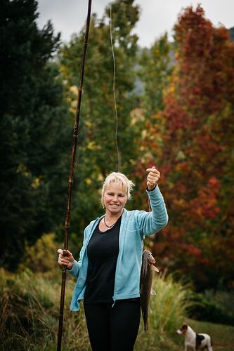 Woman outside holding a fish on a line.