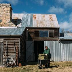 Digital Photograph - Janet Jeffs standing by Historic Stone Barn with Wheelbarrow, Ballalaba Farm, NSW, 15 Sep 2017