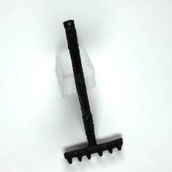 Toy rake lying down, with prongs up.
