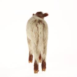 Model of white calf with brown head, shoulders and hooves. Rear view.