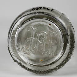 Base of clear glass bottle with raised inscription.