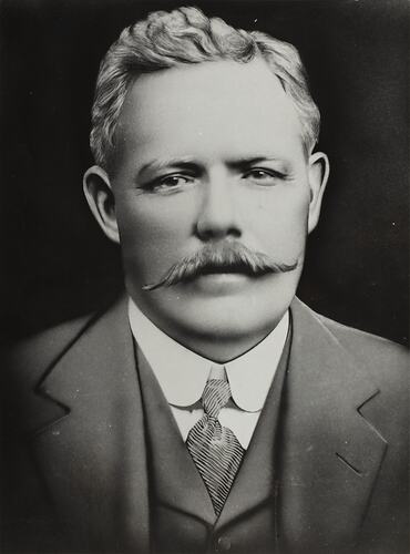 Man with moustache wearing suit.