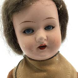 The face of a doll dressed as a friar in brown robes