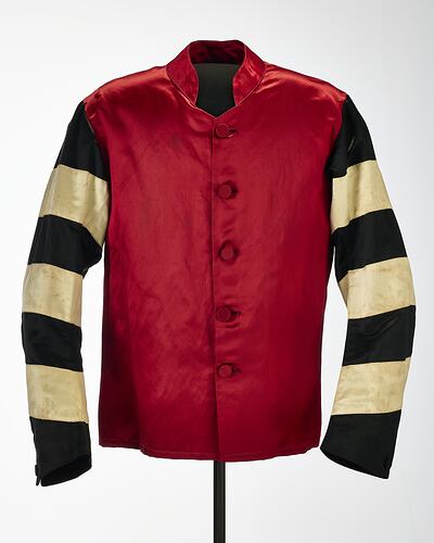 Red riding jacket with red buttons. Black and white hoops on sleeves. Short stand up red collar.