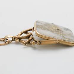 Rectangular pendant featuring white gold-bearing quartz in a gold setting, complimented by a delicate branch-like motif at the top. Profile.