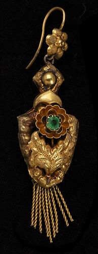 Gold and green paste pendant earring. Comprised of four connected sections with floral and leaf motifs. Gold fringe hangs from the bottom.