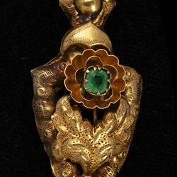 Gold and green paste pendant earring. Comprised of four connected sections with floral and leaf motifs. Gold fringe hangs from the bottom.