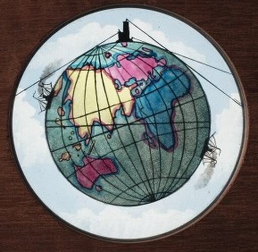 Detail of wooden slide. Has round glass slide with coloured illustration of Earth.